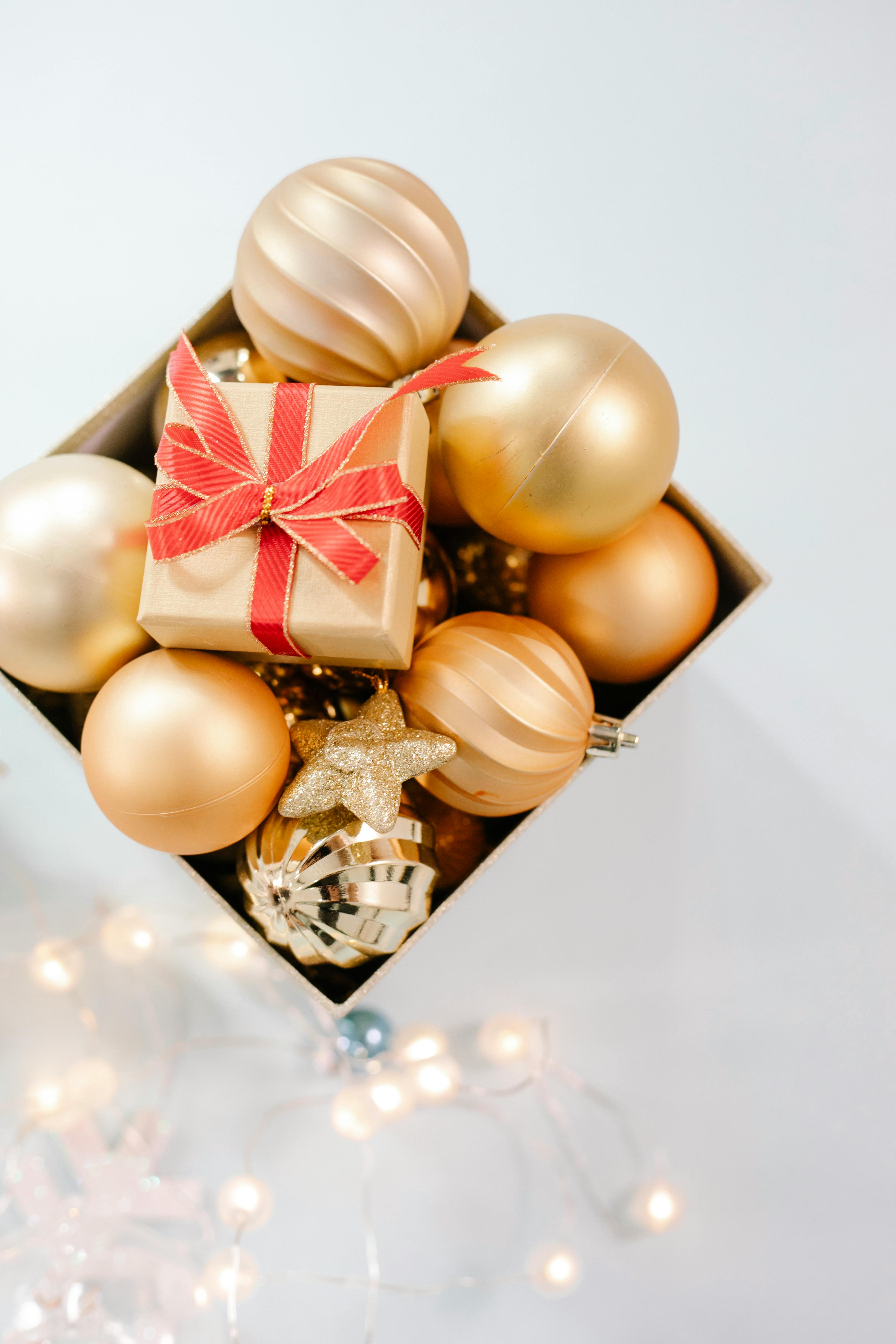 box with golden baubles placed on white surface