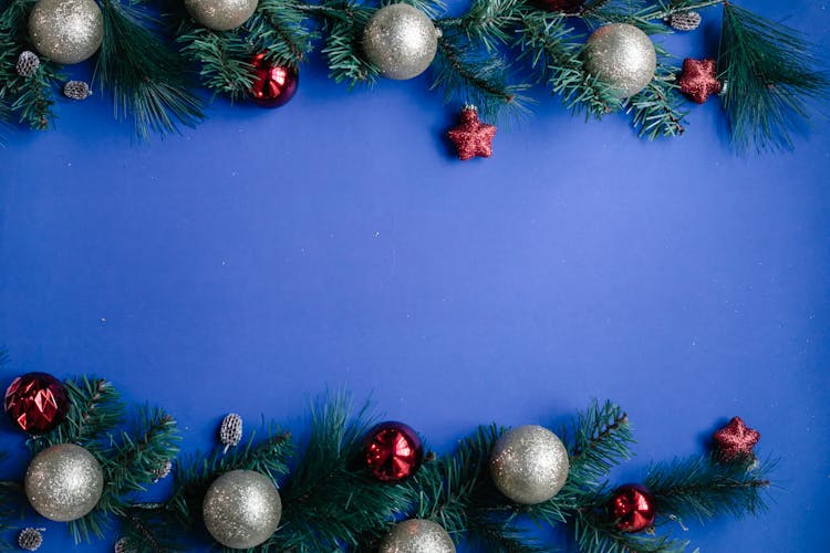 Branches Of Fir With Christmas Baubles Against Blue Background