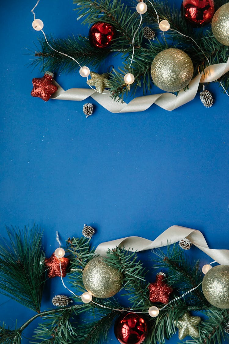 Christmas Baubles Placed On Branches Of Fir Against Blue Background