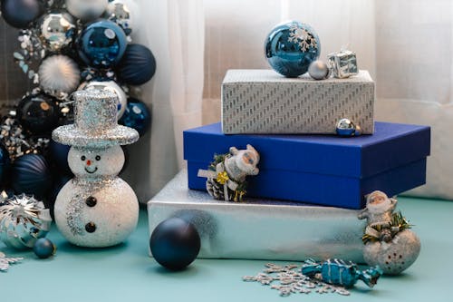 Various Christmas toys and pile of vivid colorful gift boxes placed on table near curtains