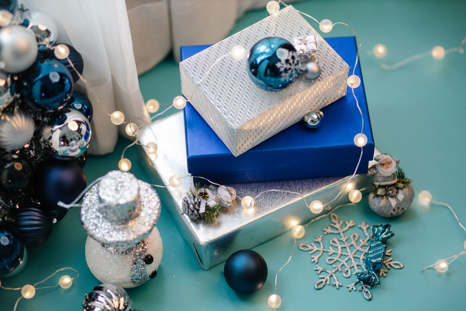 glowing fairy lights with Christmas toys, gift boxes and baubles on a table