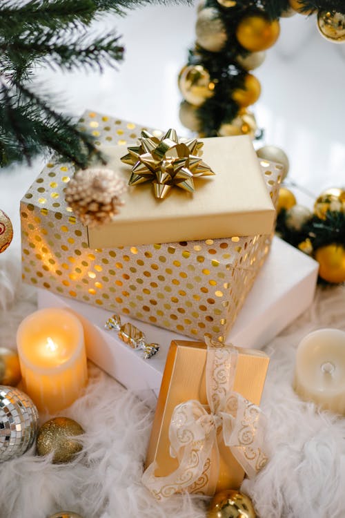 Free Festive Christmas gifts and decorations with candles on white fur, creating a warm holiday ambiance. Stock Photo