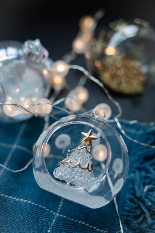 Free High angle of glass balls with small Christmas tree inside and glowing fairy lights on blue cloth Stock Photo