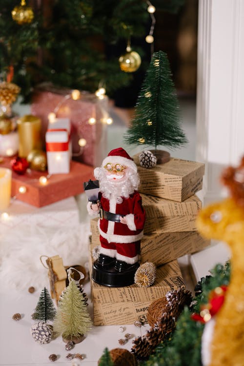 Statuetta Di Babbo Natale Accanto A Scatole Regalo In Legno Marrone