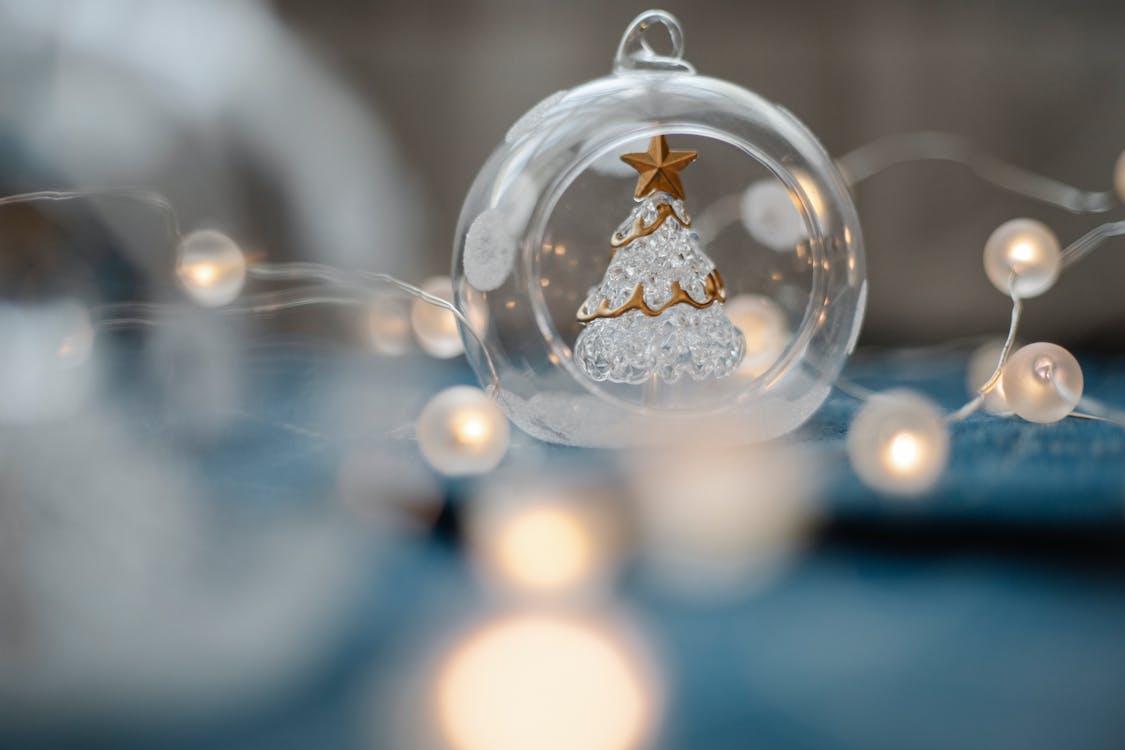 Glass Christmas tree inside transparent ball surrounded by burning garland for festive decorations