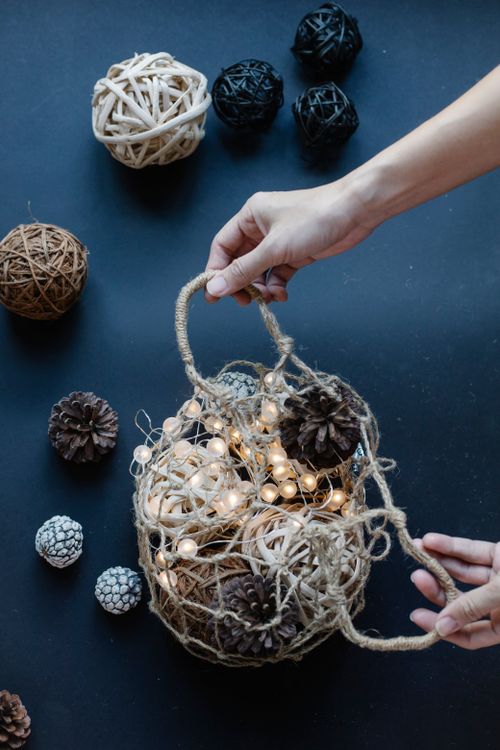 Free From above of crop anonymous person opening bag with shining garland and threads with cones Stock Photo