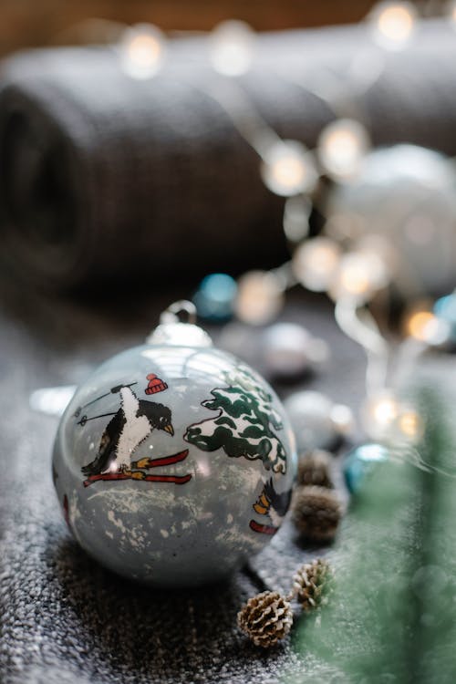 Glass ball with decorative Christmas ornament scattered with fir cones and luminous  garland