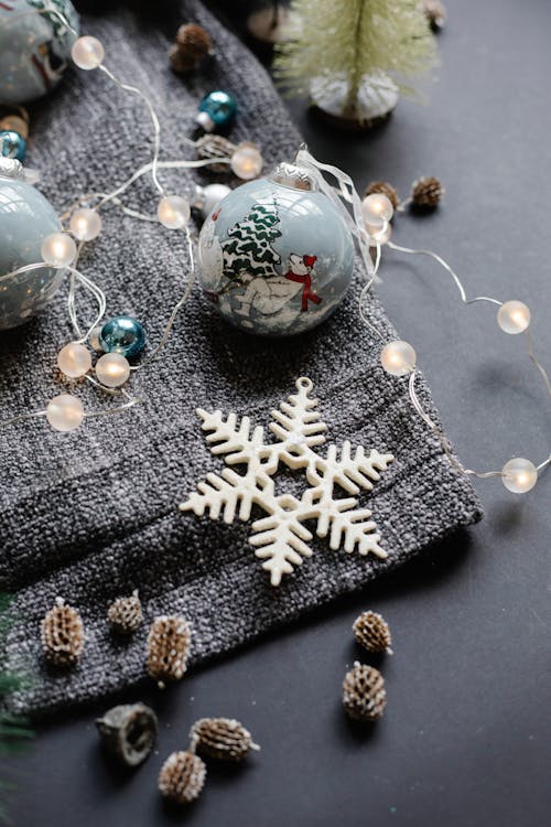 From above of various decorations consisting of shiny garland balls with fir cones placed near star for Christmas preparation