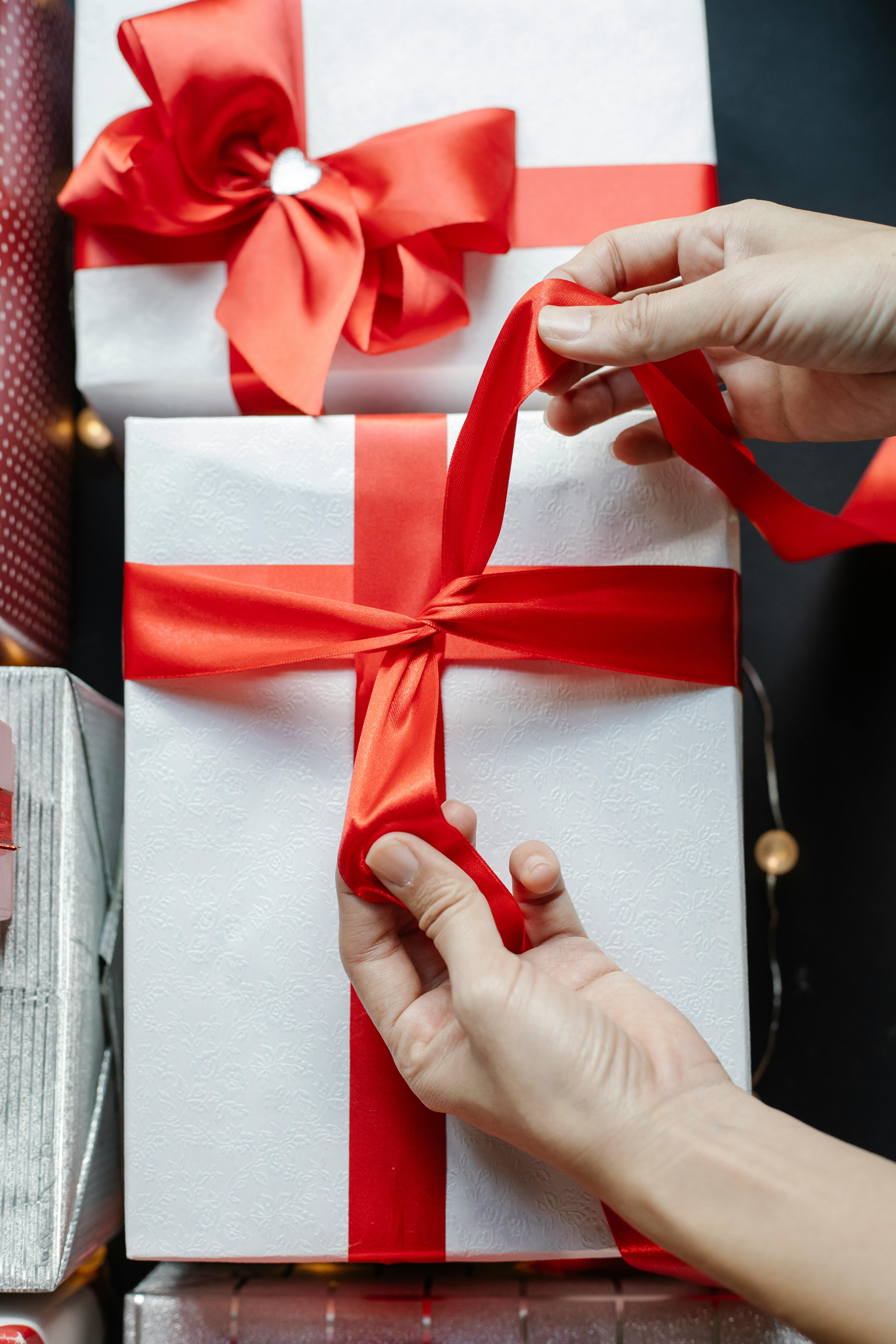 anonymous person putting ribbon on gift box