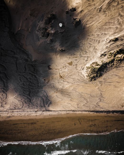 A breathtaking aerial view of a coastal landscape in New Zealand, featuring dunes, beach, and ocean.