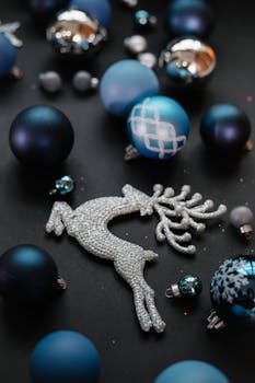 High angle of Christmas decorative silver reindeer near different blue balls on black background in light room