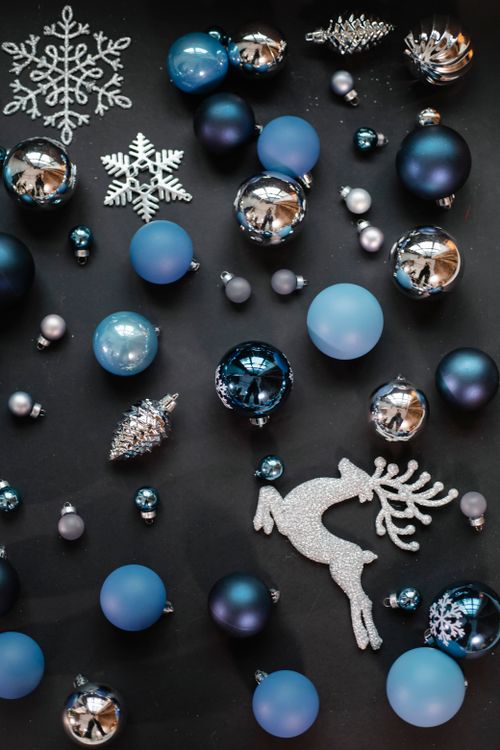 Free From above of Christmas decorative different blue and silver balls near sparkling reindeer and snowflakes near cone toy in light place on black surface Stock Photo