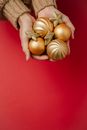 Anonymous woman showing heap of golden Christmas tree baubles