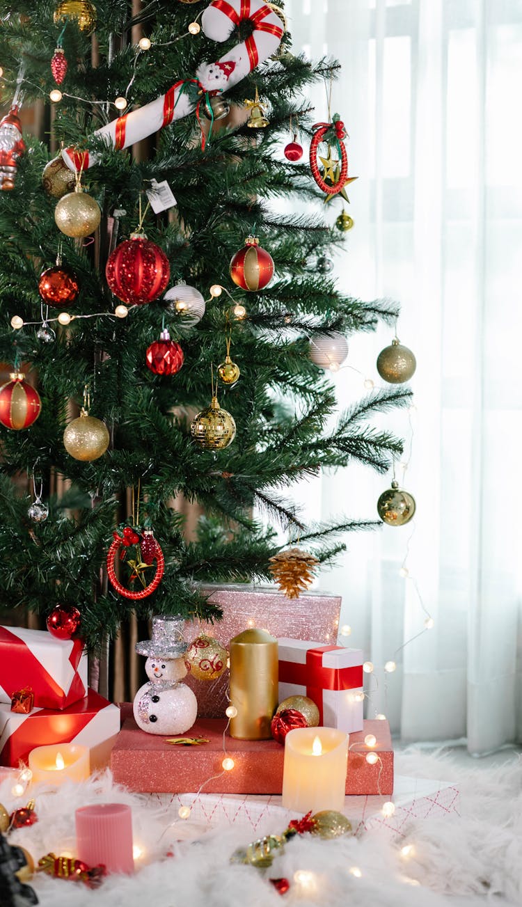 Decorated Christmas Tree With Wrapped Gifts And Candles In Cozy Apartment