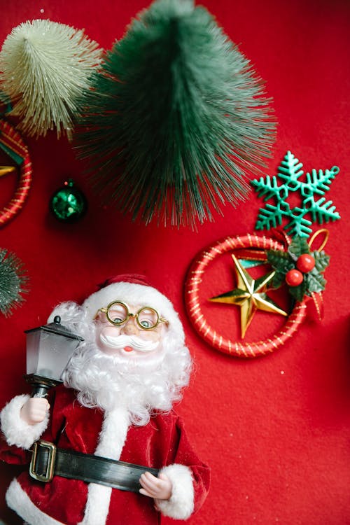 Fir tree miniature with Christmas decorations and Santa Claus toy placed on red table