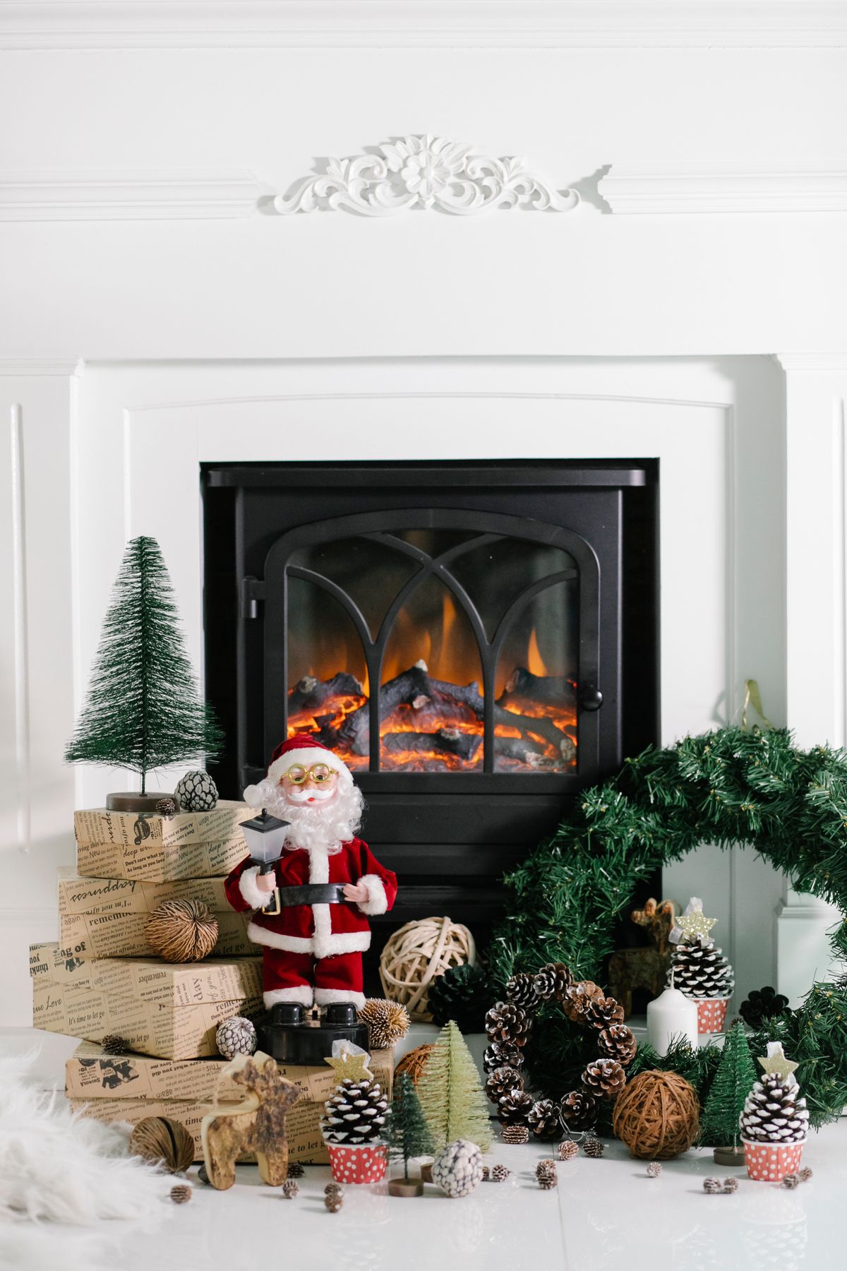 Santa Claus figure with Christmas decorations and a fir wreath near a fireplace