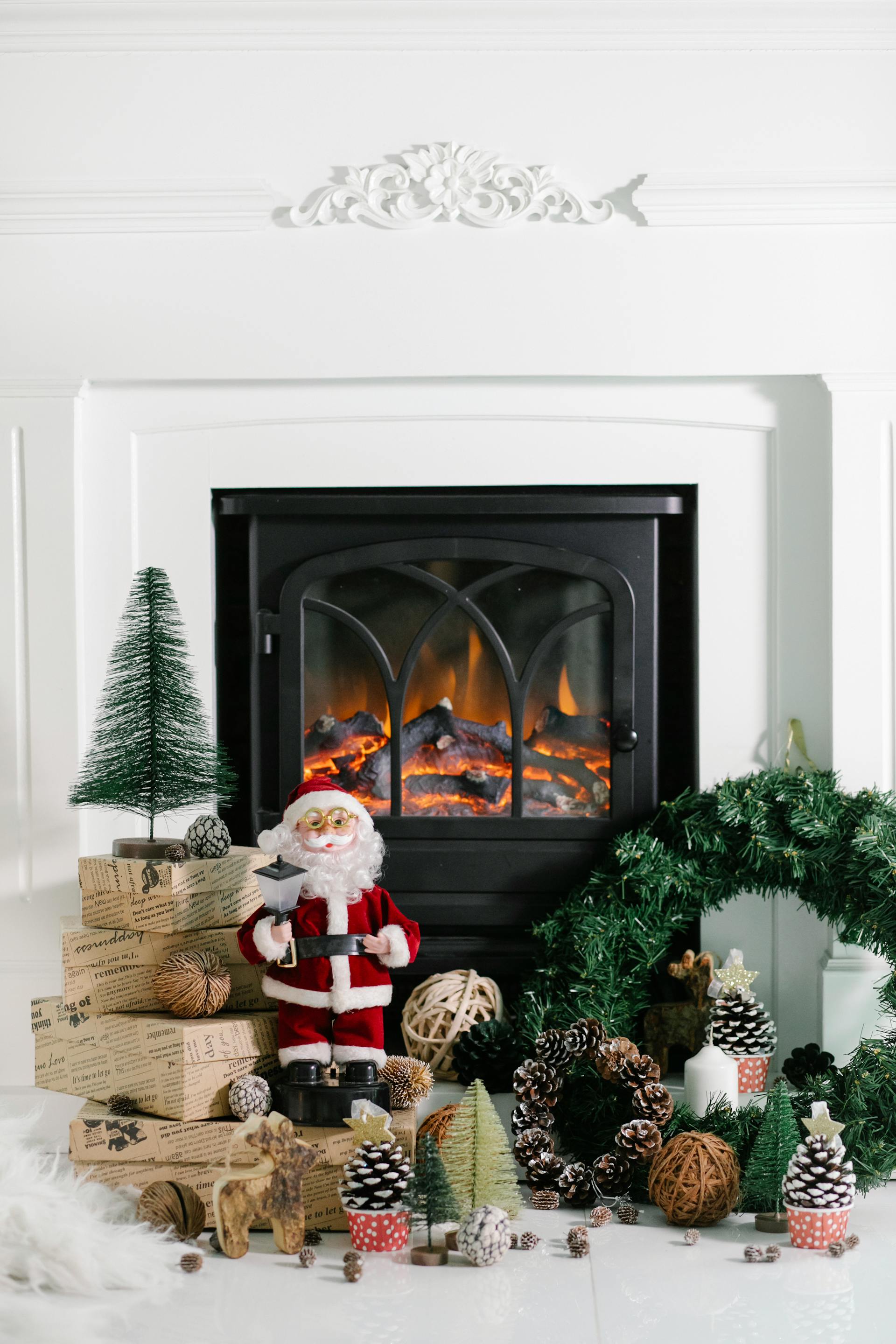 A warm festive fireplace scene with Santa figurines and holiday decorations