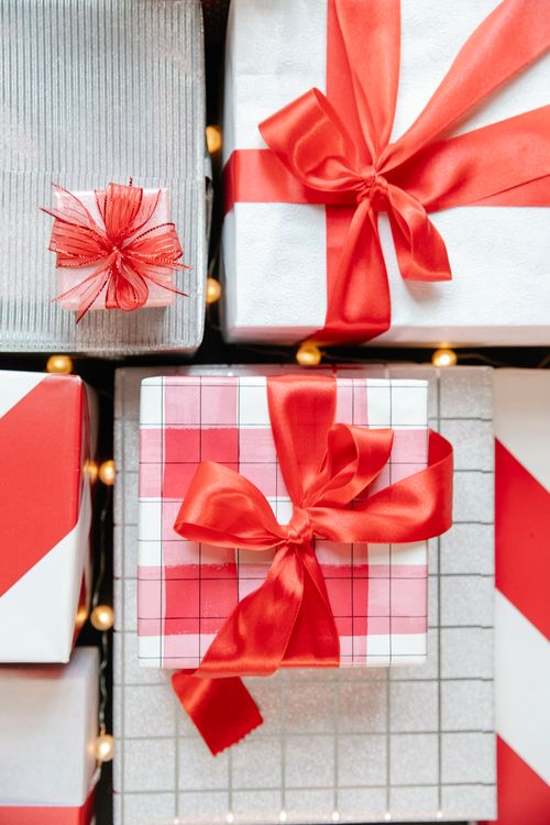 Free Top view of various wrapped gift boxes decorated with red ribbons and placed near glowing garland during Christmas holiday Stock Photo