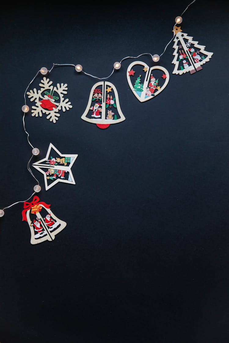 Set Of Wooden Christmas Baubles And Garland On Black Surface