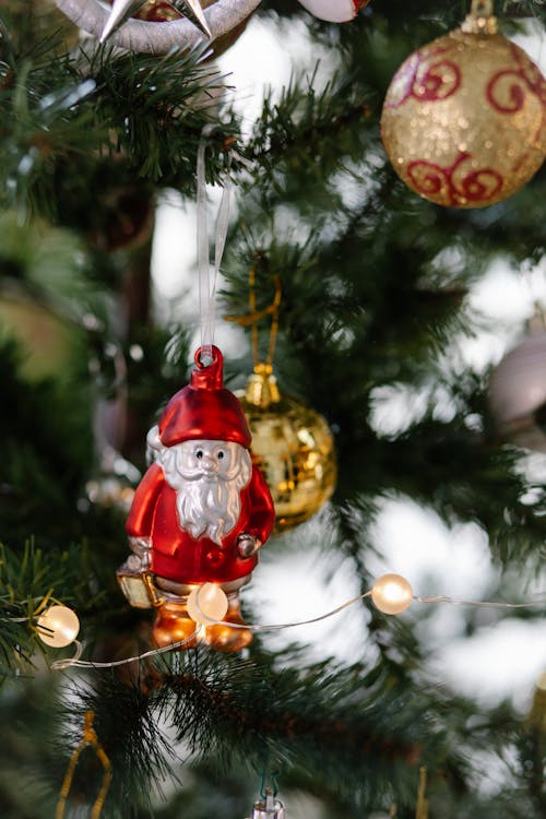 Spruce tree with assorted baubles and Saint Nicholas statuette above shiny garland during New Year holiday