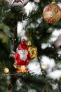 Spruce tree with assorted baubles and Saint Nicholas statuette above shiny garland during New Year holiday