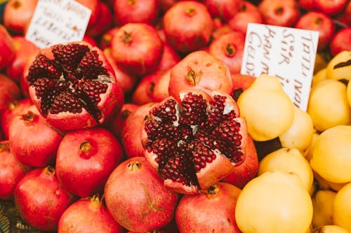 Close-Up Photograph of Red Pomegranates Beside Yellow Quinces