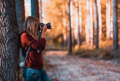 Femme Se Penchant En Arrière Sur Le Tronc D'arbre à L'aide De L'appareil Photo Reflex Numérique Noir Pendant La Journée