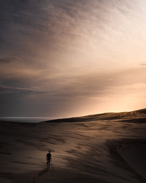Photo of a Man Standing in a Desert with Sand 