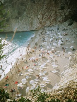A captivating aerial view of Kaputas Beach in Antalya, Türkiye, showcasing sunbathers and umbrellas on a sunny summer day.