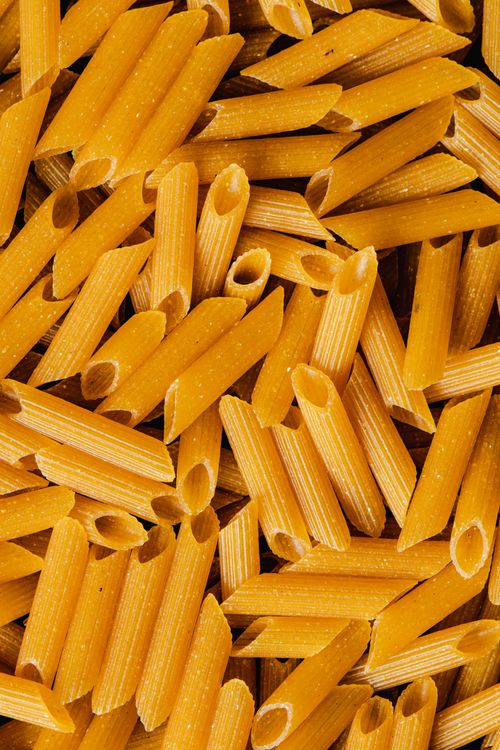 Free Detailed shot of uncooked penne pasta with distinct texture, ideal for food backgrounds. Stock Photo