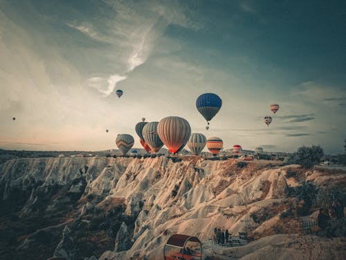 Assorted air balloons flying above sandy mountains