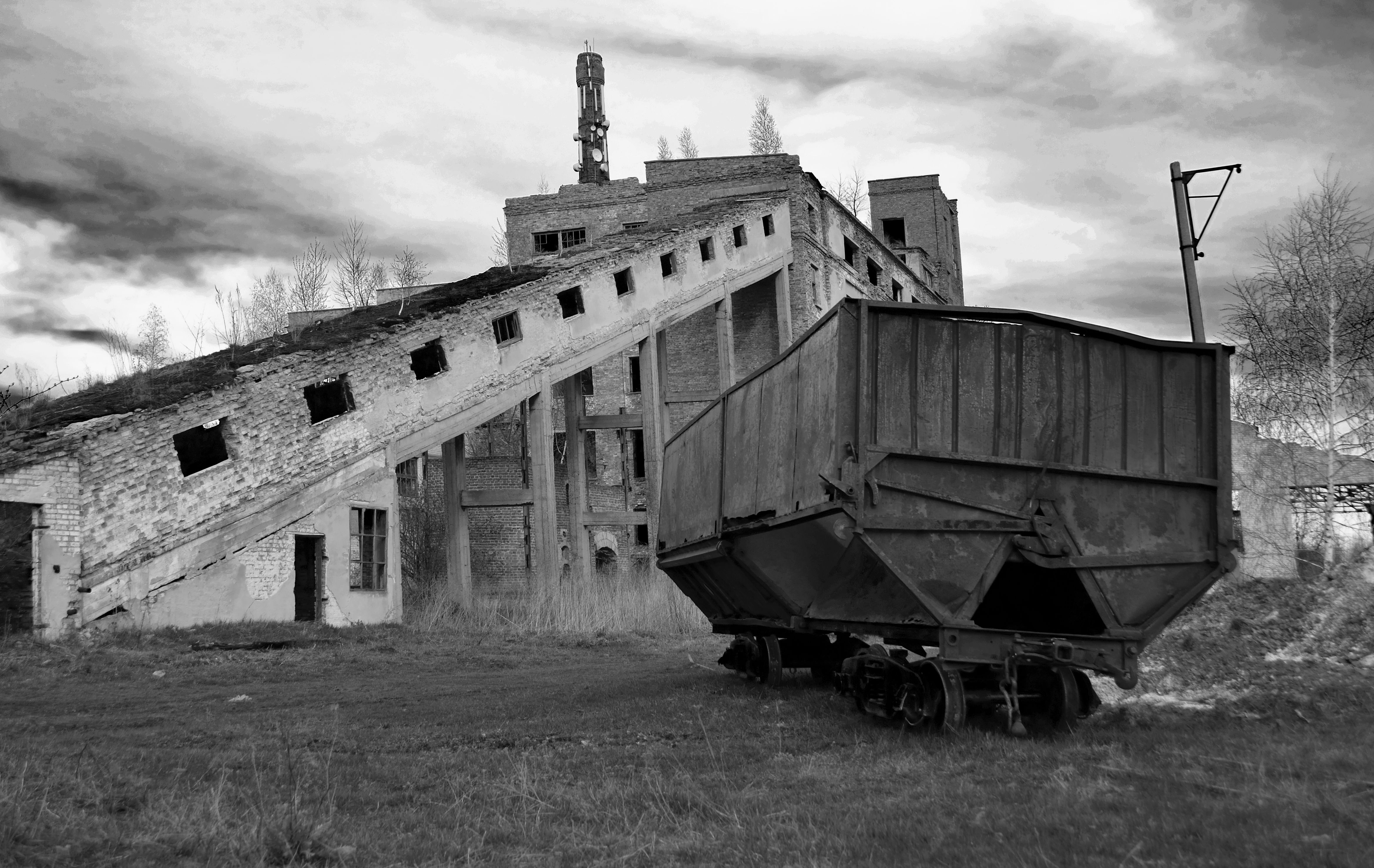 Black and white photo of an abandoned industrial building with a train freight car.