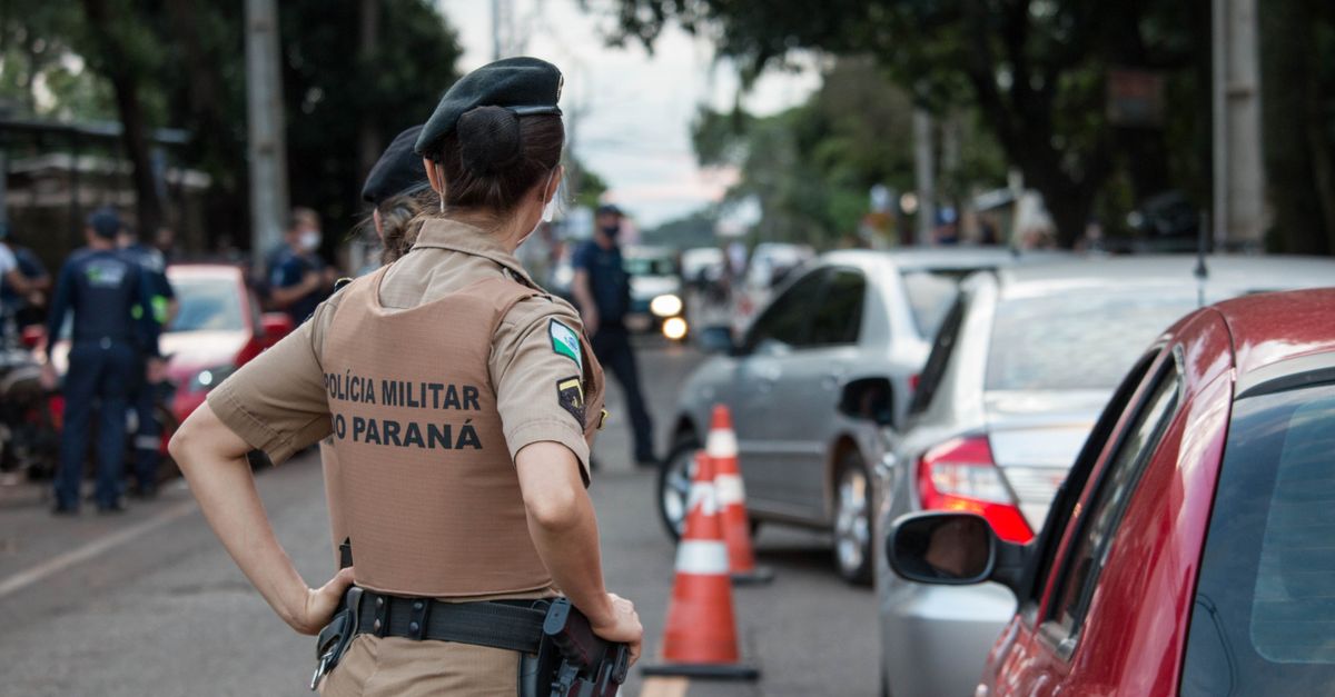 Back view of a police officer in uniform controlling traffic on a busy road.
