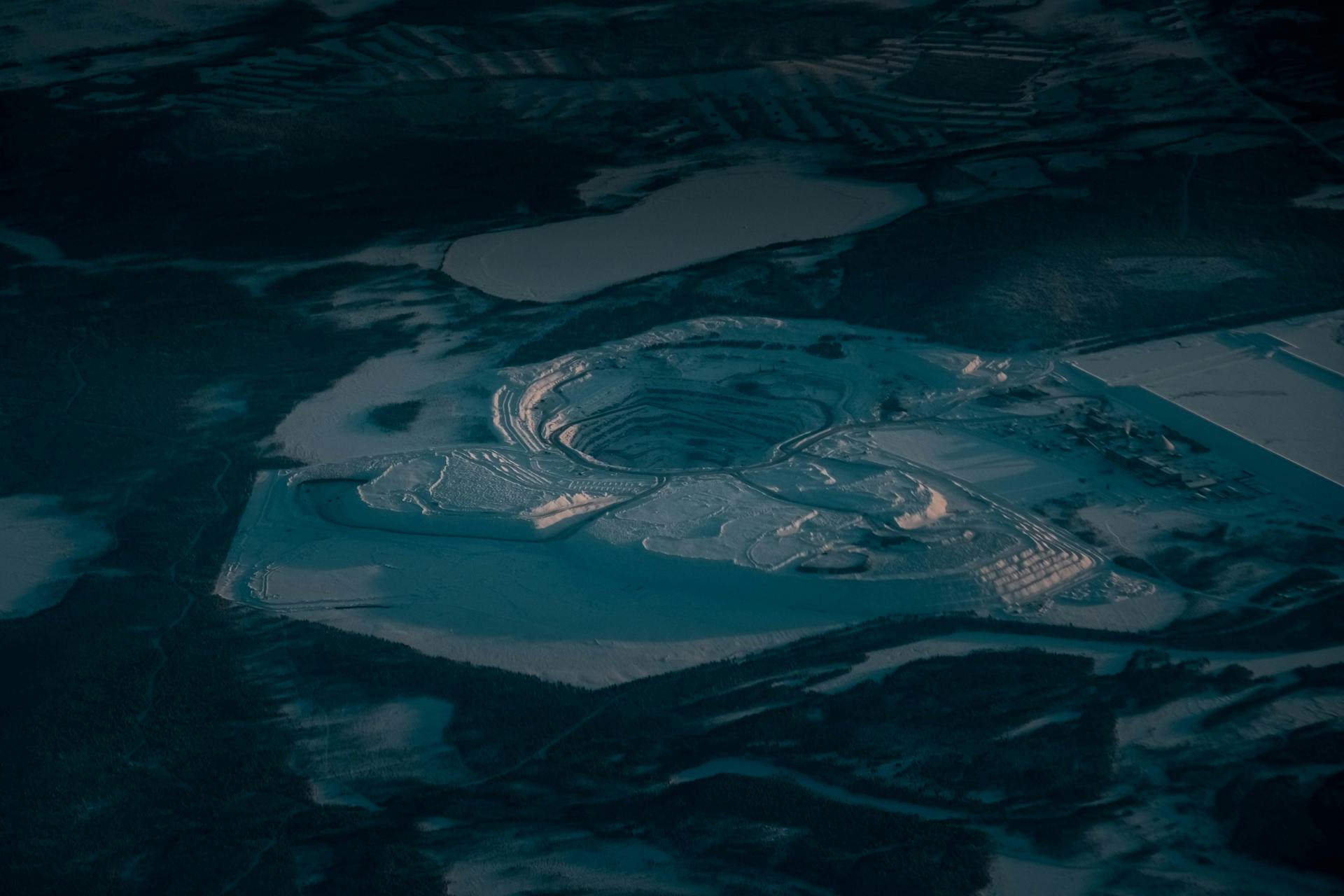 Picturesque drone view of rocky steps at open pit mine covered with snow in industrial terrain in evening