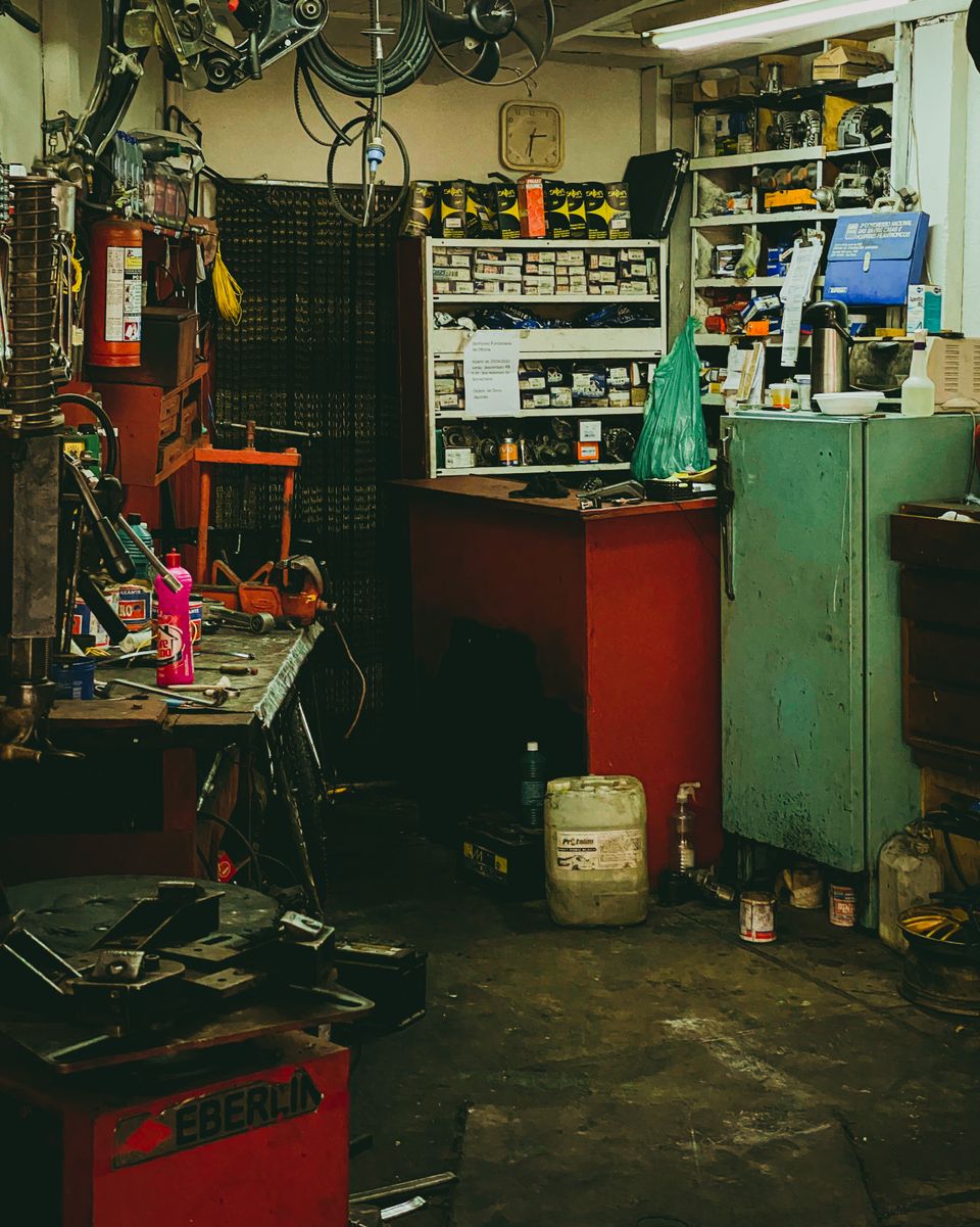 Cluttered auto repair workshop garage with tools and equipment along the walls