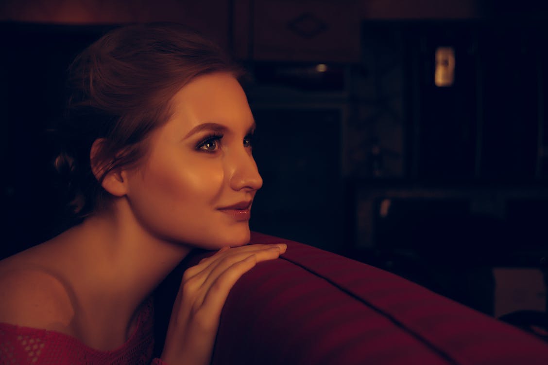 Woman Posing on Back of Red Sofa