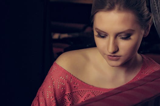 A serene portrait of a young woman looking down, captured in a warm, intimate setting.