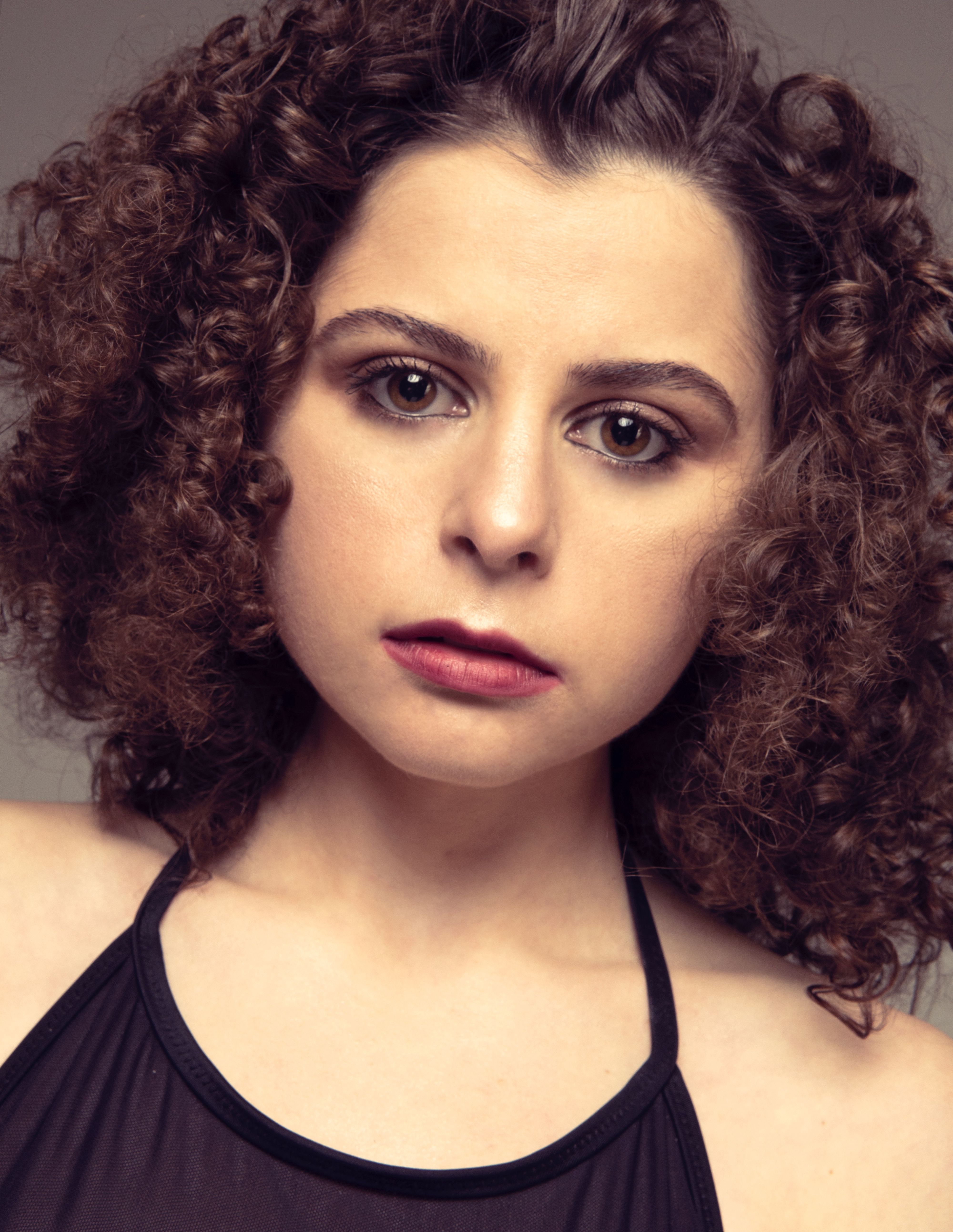 Close-up portrait of a woman with curly hair and red lips, showcasing beauty and elegance.