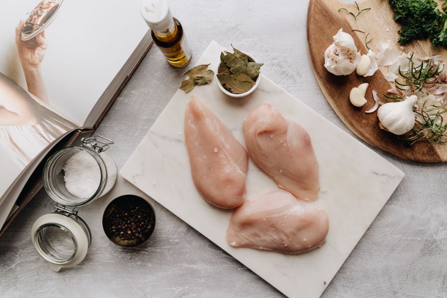 Fotografía de pechugas de pollo crudas con ingredientes sobre una tabla de madera