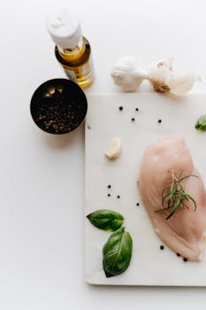 Flat lay of raw chicken with basil, garlic, and peppercorns for a delicious meal prep.