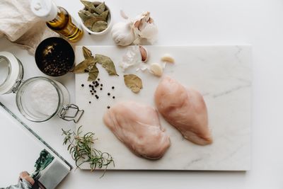 Raw chicken breasts on a marble board with herbs. Photo by alleksana on Pexels.