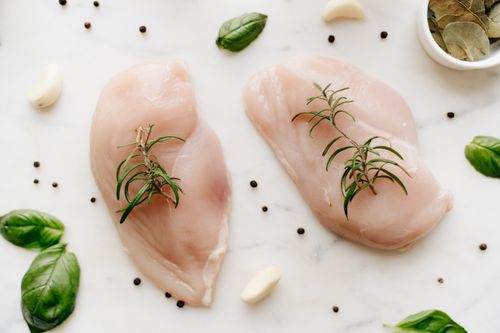 Free Close-up of raw chicken breasts garnished with rosemary on a marble surface with herbs and spices. Stock Photo