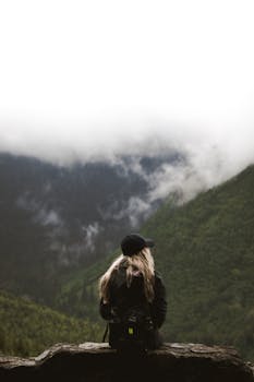 A lone female hiker enjoys a tranquil view of misty mountains in Montana.