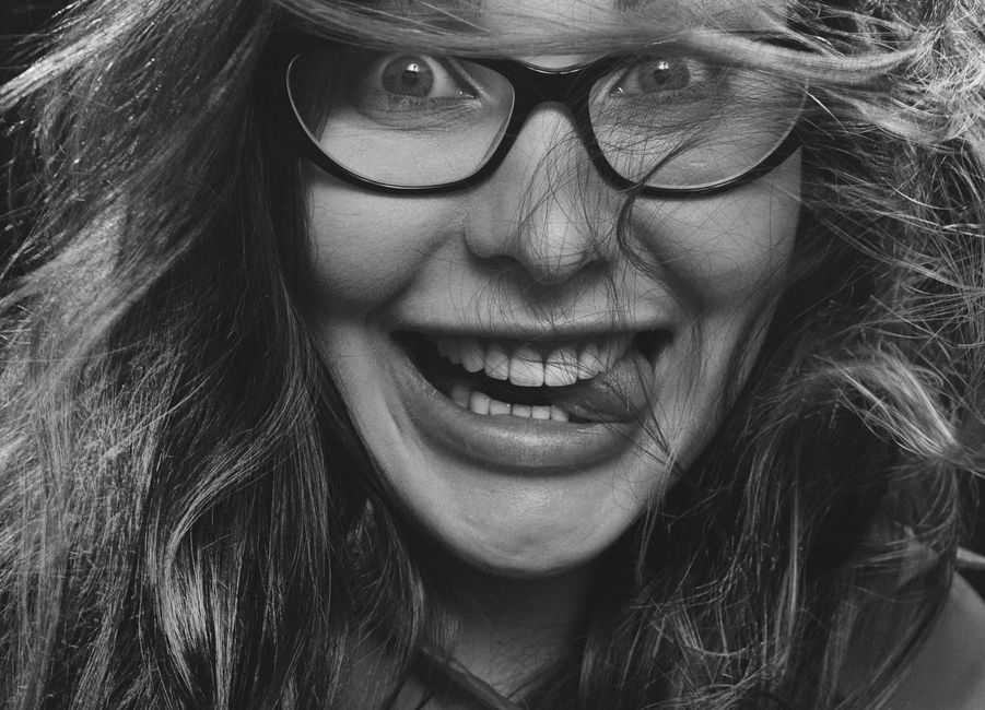 Vibrant close-up of a woman gleefully posing with glasses in grayscale.