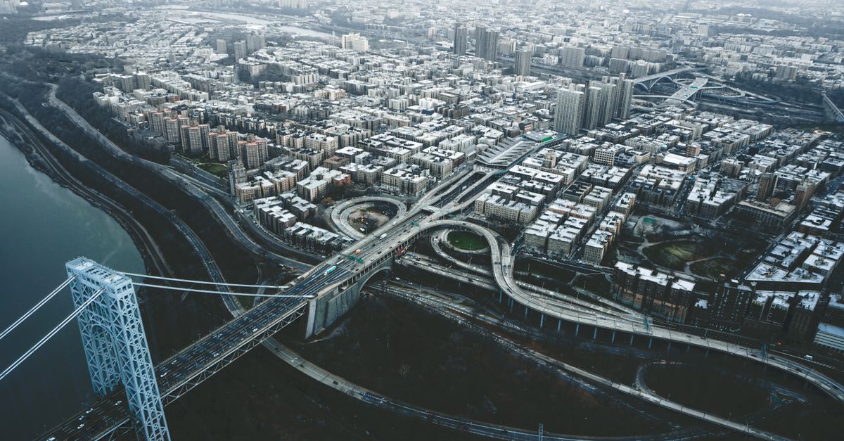 Drone view of George Washington Bridge crossing river and connecting districts of New York City against cloudy sky