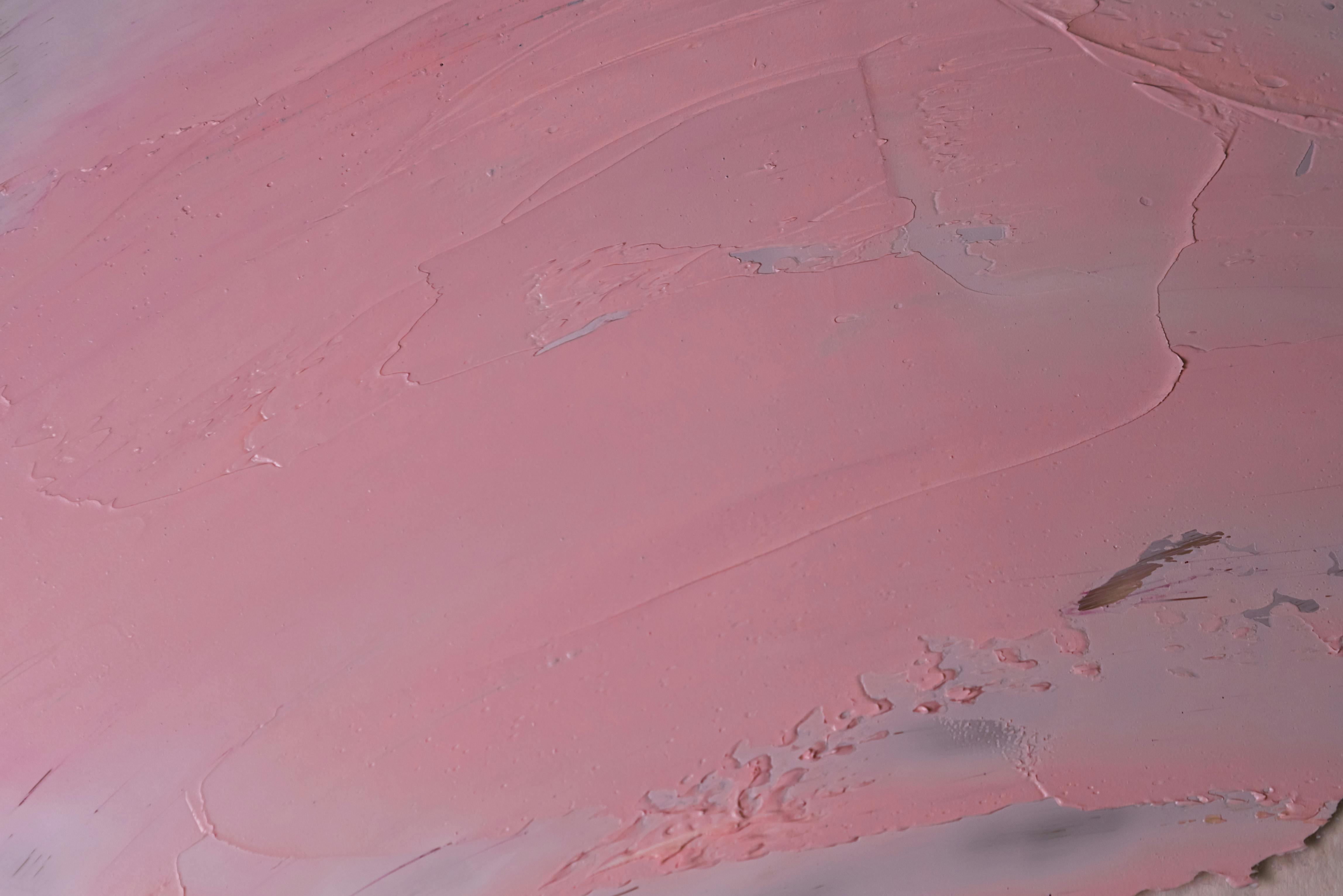 A close-up view of a pink textured surface with brush strokes and subtle patterns.
