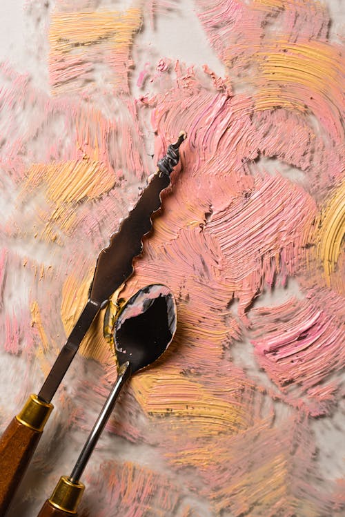 粉色和蓝色的抽象绘画上的不锈钢勺子