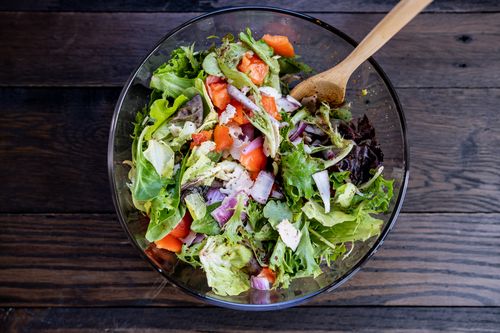 Free Top view of a fresh mixed vegetable salad in a glass bowl with wooden spoon on a rustic surface. Stock Photo