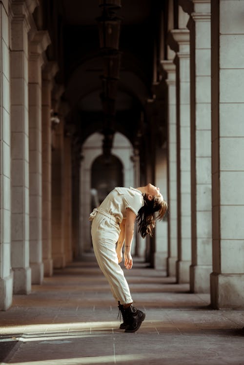 Free Side view full body of woman standing on tiptoes between high columns during dance rehearsal Stock Photo