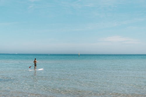 Shirtless Man Standing on White Surfboard